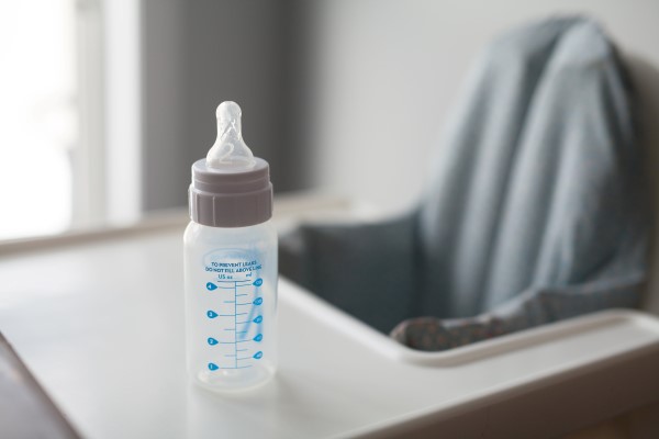 Photo of a baby's milk bottle on a high chair.