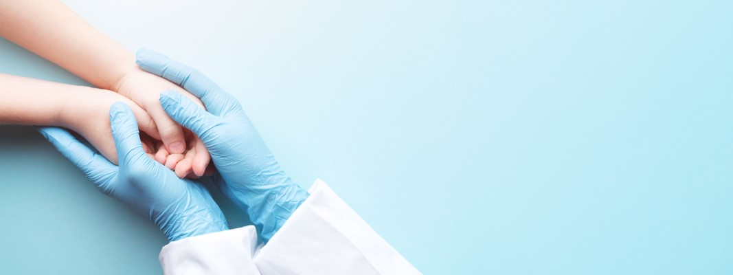 doctor's hands holding young patient's hands